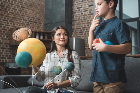 Little boy and his young mother creating a Solar system model for school projectの写真素材