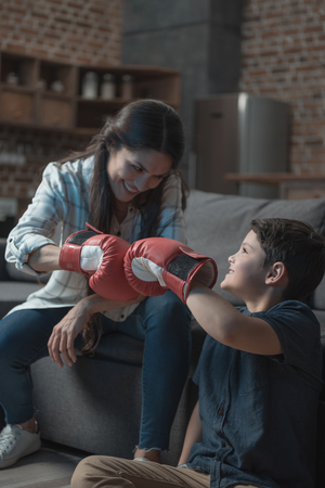 Little boy and his young mother fistbumping while wearing boxing glovesの写真素材