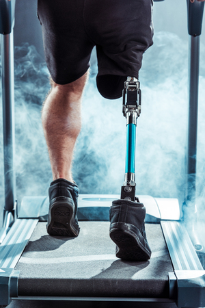 cropped shot of sportsman with leg prosthesis training on treadmillの写真素材