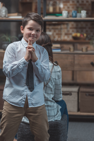 Little boy in shirt and tie posing and making gesture as if holding pistolの写真素材