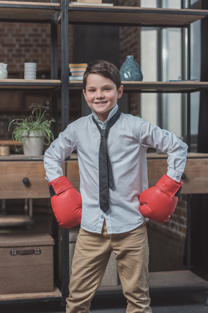 Little boy in shirt and necktie wearing boxing gloves, posing with hands on hipsの写真素材