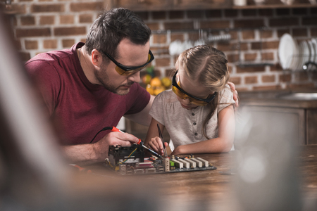 Father teaching daughter to braze at the kitchen table  の写真素材