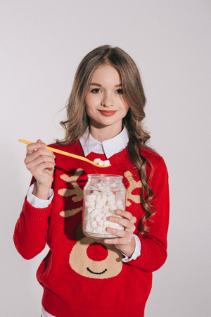 beautiful teenage girl holding marshmallows and smiling at camera isolated on greyの写真素材
