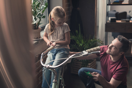 daughter sitting on repaired bicycle at home の写真素材