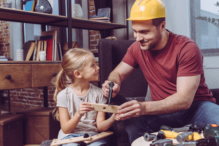 Father and daughter making a wooden frame with toy tools at home の写真素材