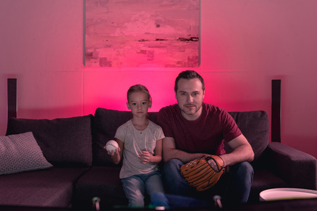 Father and daughter watching a baseball game at home