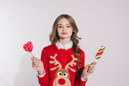 beautiful teenage girl holding candies and smiling at camera isolated on grey の写真素材