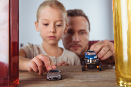 Portrait of daughter and father playing small car toys at home の写真素材