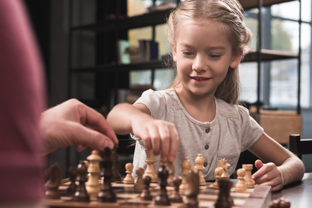 Preschooler kid playing chess with her father at homeの写真素材