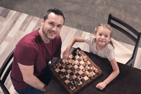 Top view of Father and daughter posing with chess board at home の写真素材