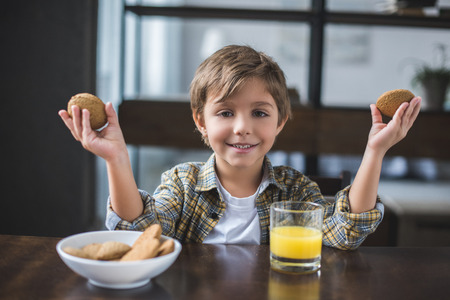 portrait of smiling little boy looking at camera during breakfast at homeの写真素材