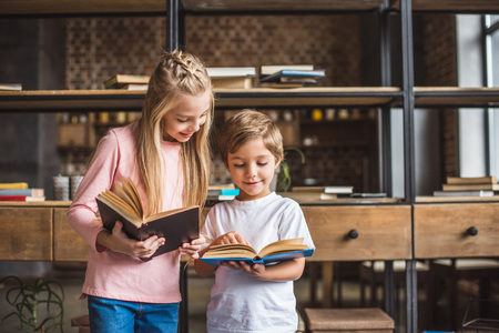 portrait of smiling siblings with books in hands at homeの写真素材