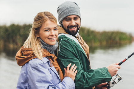 happy young couple fishing together and looking at cameraの写真素材