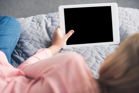 partial view of kid holding tablet with blank screen at homeの写真素材
