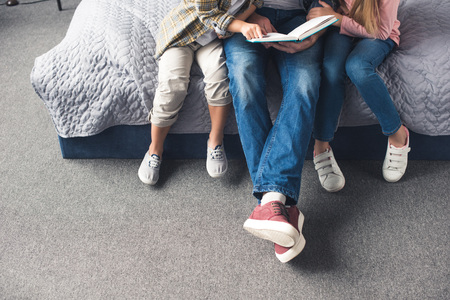 cropped shot of father and kids reading book together at homeの写真素材