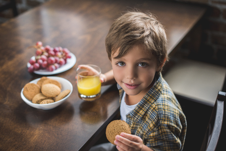 high angle view of adorable little boy looking at camera during breakfast at homeの写真素材