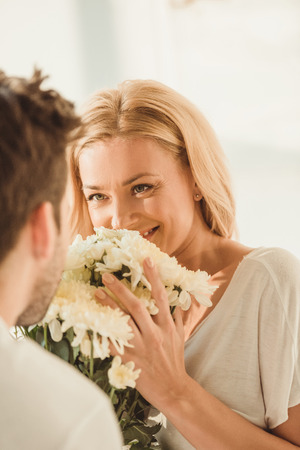 man presenting flowers for happy young girlfriend at morningの写真素材