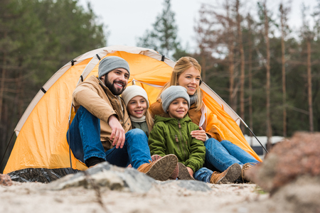 happy family sitting near camping tent on natureの写真素材