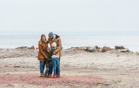 beautiful family emracing on seashore on cold autumn dayの写真素材