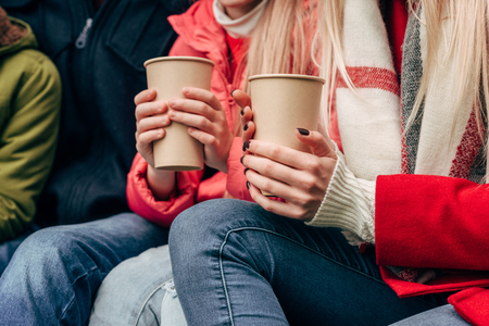 cropped shot of family holding paper cups while sitting together outdoorsの写真素材