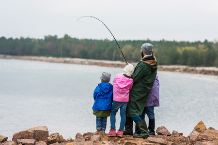 family fishing together on rocky coast 