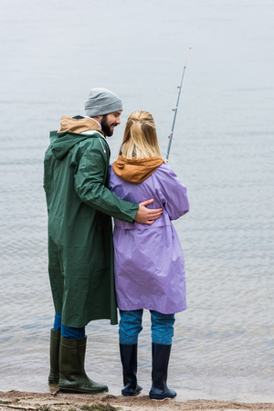 young couple in raincoats fishing togetherの写真素材