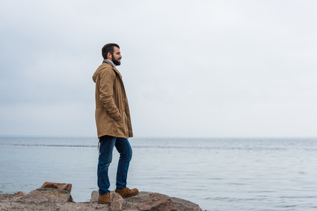 lonely man standing on rocky seashoreの写真素材