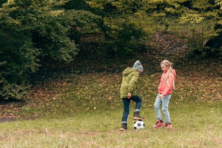 cute little kids playing soccer in autumn parkの写真素材