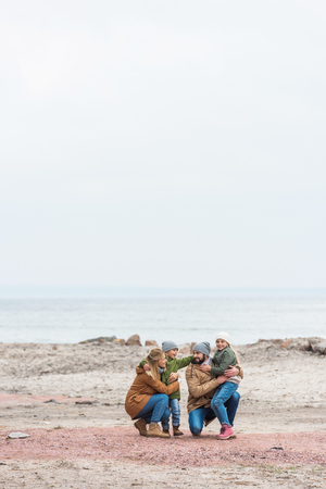 happy family emracing on seashore on cold autumn dayの写真素材