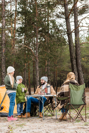 happy young family on camping in forest drinking hot teaの写真素材