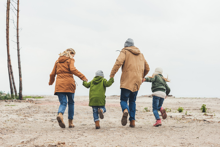 back view of family running together and holding hands on natureの写真素材