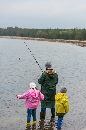 father and two little kids fishing together at mountain lakeの写真素材
