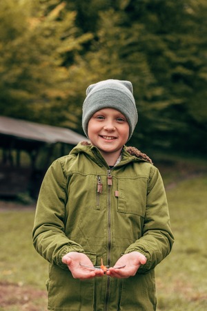 cute little boy holding toy plane and smiling at camera in autumn parkの写真素材