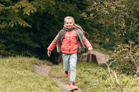 cute little child smiling at camera and running in autumn parkの写真素材