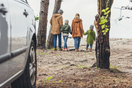 family walking and holding hands on nature with car on foregroundの写真素材