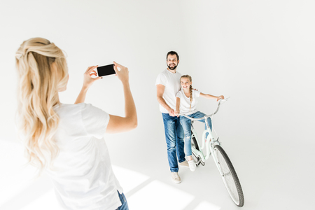 young woman photographing family with smartphone isolated on whiteの写真素材