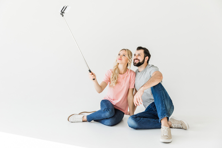 beautiful happy young couple taking selfie with smartphone isolated on whiteの写真素材