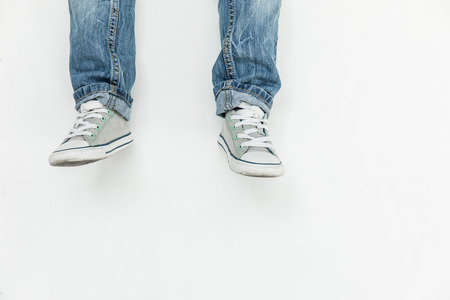 low section of child in jeans and shoes posing isolated on white