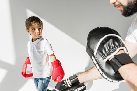 cropped shot of father training cute little son in boxing gloves on whiteの写真素材