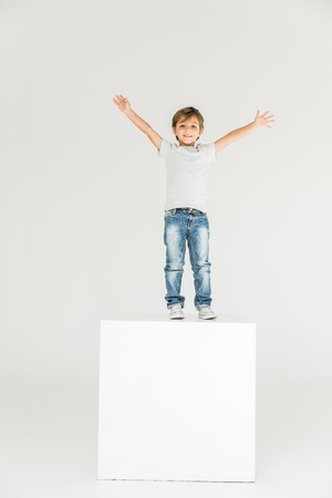 adorable little boy raising hands and smiling at camera isolated on white の写真素材
