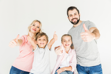happy family showing thumbs up and smiling at camera isolated on whiteの写真素材