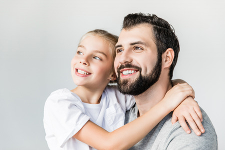 beautiful happy father and daughter hugging and looking away isolated on whiteの写真素材