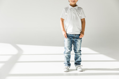 cropped shot of cute smiling little boy standing on whiteの写真素材