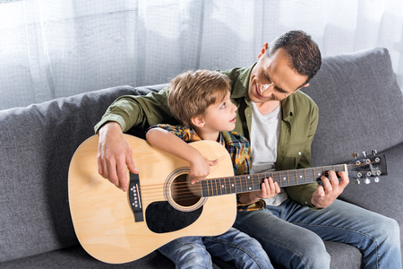 handsome happy father and little son playing guitar togetherの写真素材