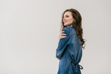 beautiful smiling young woman in denim shirt looking away isolated on greyの写真素材