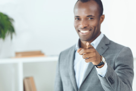 smiling african american man pointing on cameraの写真素材