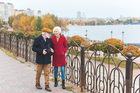 senior tourist couple with photo camera walking on quayの写真素材