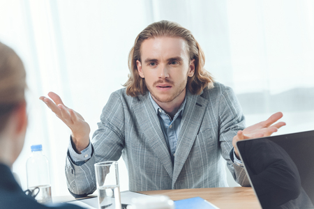 man sitting at table and looking to woman  at office spaceの写真素材