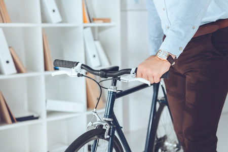 cropped image of businessman holding bike in officeの写真素材
