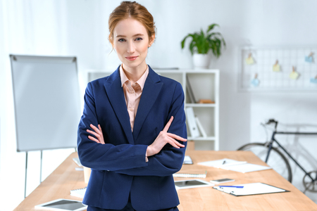 businesswoman with arms crossed looking at camera at office space の写真素材